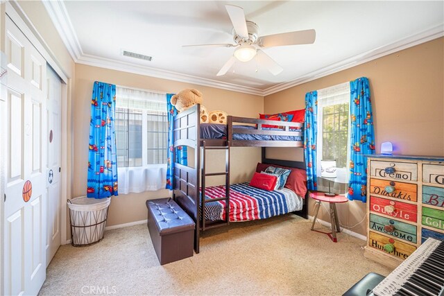 bedroom featuring crown molding, ceiling fan, carpet floors, and a closet