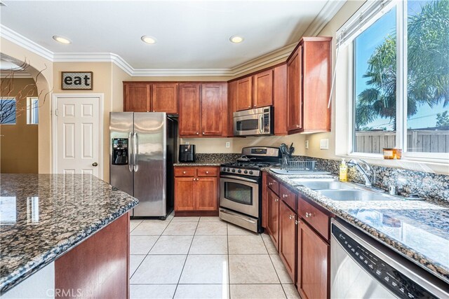 kitchen featuring dark stone countertops, sink, ornamental molding, appliances with stainless steel finishes, and light tile patterned floors