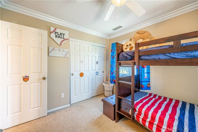 carpeted bedroom with ornamental molding, ceiling fan, and a closet