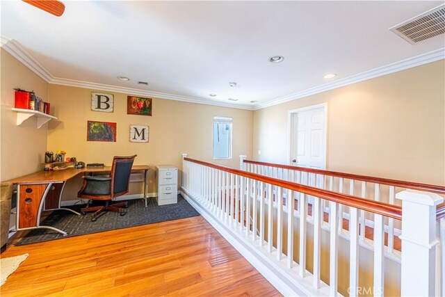 office space with crown molding, built in desk, and hardwood / wood-style floors