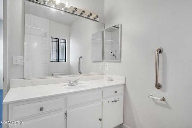 bathroom with toilet, vanity, and tiled shower