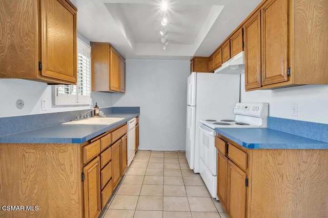 kitchen featuring white appliances, sink, rail lighting, a raised ceiling, and light tile patterned floors