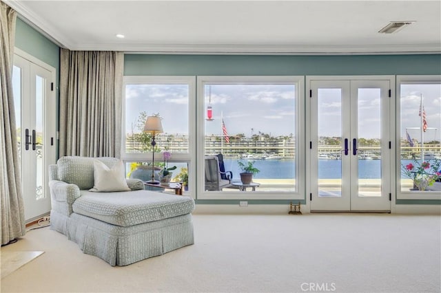 living area featuring ornamental molding, a water view, french doors, and carpet flooring