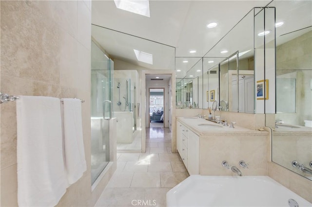 bathroom featuring vaulted ceiling with skylight, tile patterned flooring, vanity, tile walls, and independent shower and bath