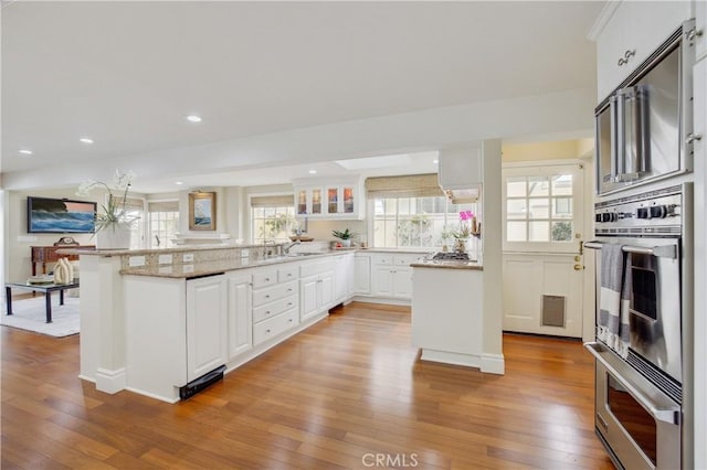 kitchen with wood-type flooring, a kitchen breakfast bar, white cabinetry, and kitchen peninsula