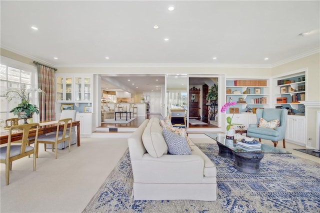 living room featuring light colored carpet, crown molding, and built in features