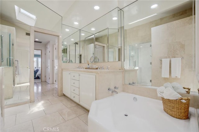 bathroom featuring vanity, tile patterned flooring, tile walls, plus walk in shower, and a skylight