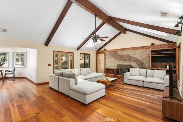 living room featuring hardwood / wood-style floors, high vaulted ceiling, a wood stove, and a wealth of natural light