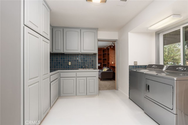 interior space featuring gray cabinets, tasteful backsplash, separate washer and dryer, and sink