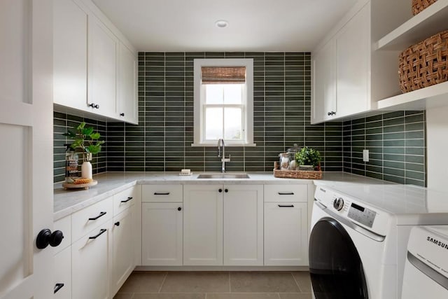 laundry room with washer and clothes dryer, sink, light tile patterned floors, and cabinets