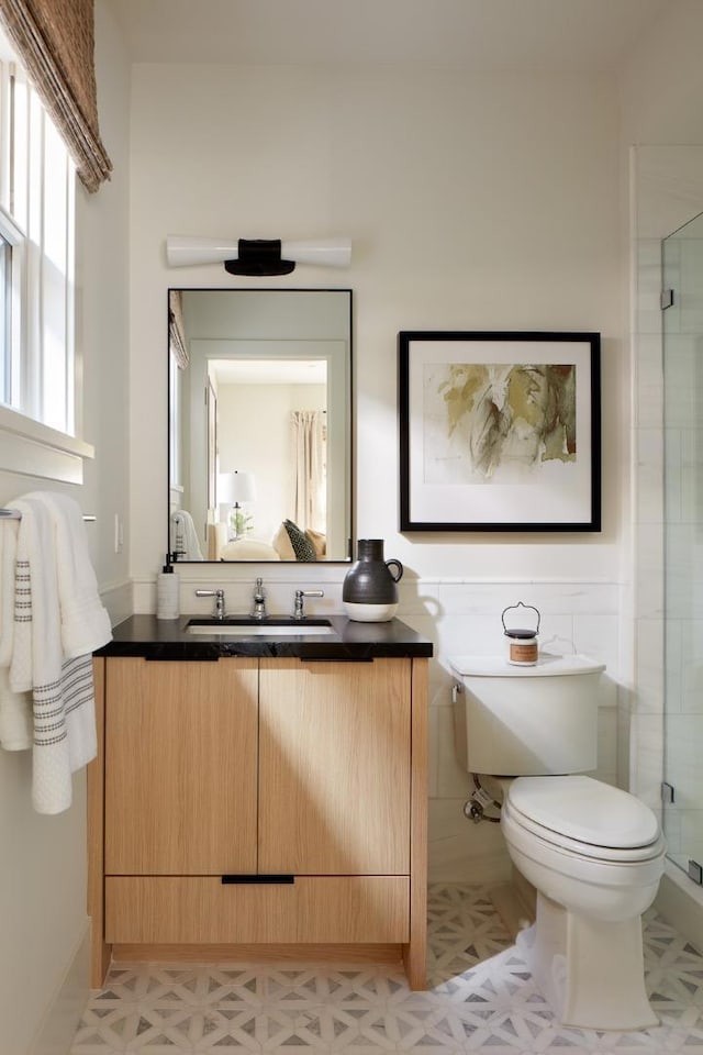 bathroom with toilet, vanity, tile patterned floors, and a shower with door