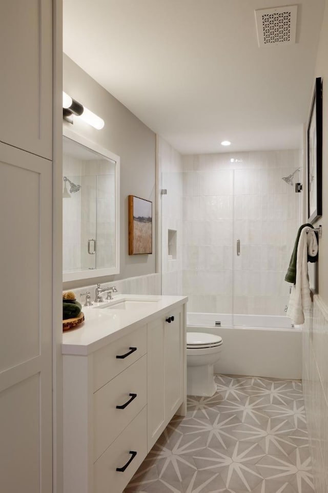 full bathroom featuring vanity, tiled shower / bath combo, and toilet