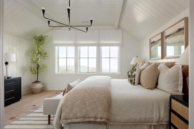 bedroom with light wood-type flooring, lofted ceiling with beams, and a notable chandelier