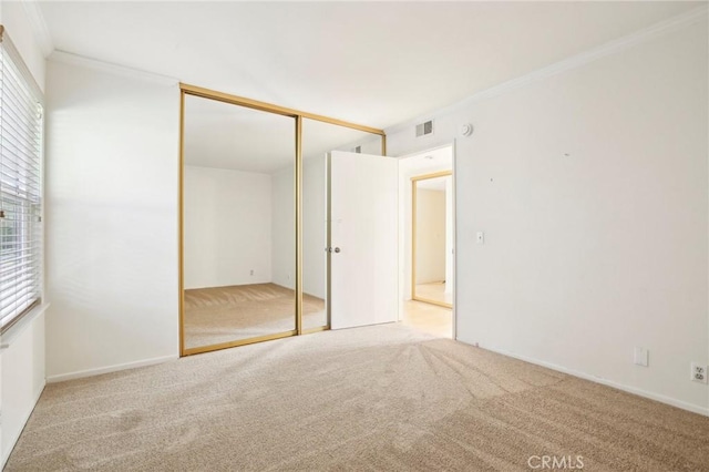 unfurnished bedroom with light colored carpet, a closet, and crown molding