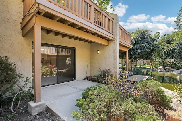 view of exterior entry featuring a balcony and a patio