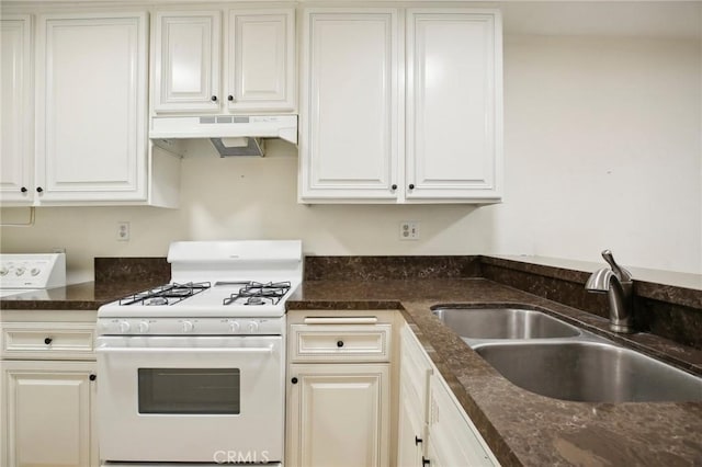 kitchen with white cabinetry, dark stone countertops, white range with gas stovetop, and sink