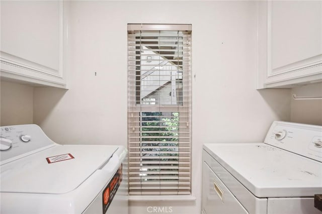 clothes washing area with washer and dryer and cabinets