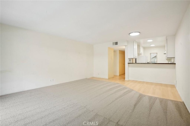 unfurnished living room featuring light carpet