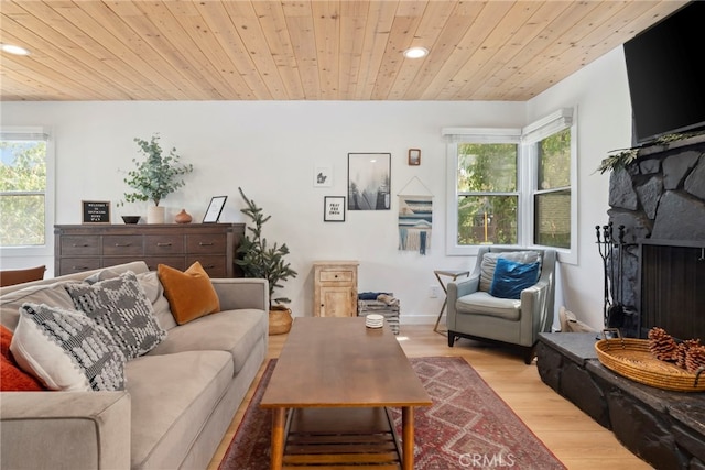 living room featuring light hardwood / wood-style flooring, wood ceiling, and a fireplace