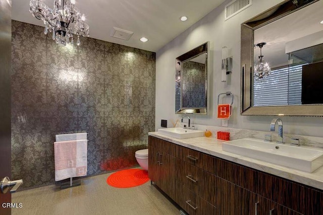 bathroom with a notable chandelier, toilet, and vanity