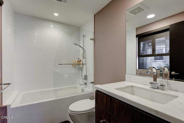 full bathroom featuring vanity, tiled shower / bath combo, and toilet