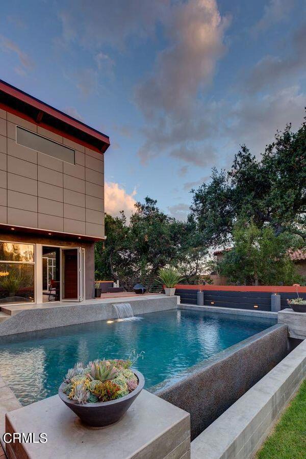 pool at dusk featuring pool water feature