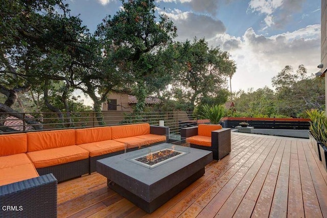 deck featuring an outdoor living space with a fire pit