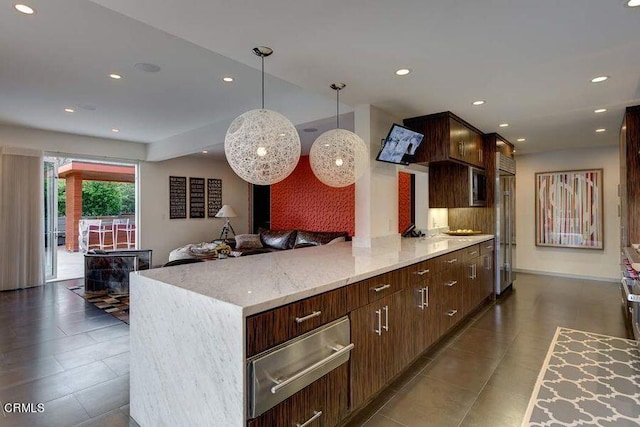 kitchen with dark tile patterned flooring, decorative light fixtures, light stone counters, and dark brown cabinets