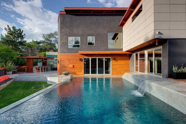 rear view of property featuring pool water feature and a patio area