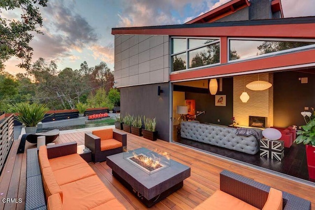 patio terrace at dusk with an outdoor living space with a fire pit and a wooden deck