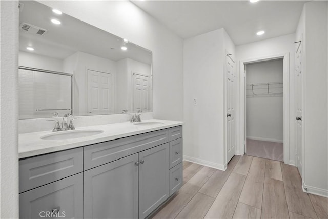 bathroom featuring hardwood / wood-style flooring, vanity, and a shower with door