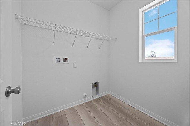 clothes washing area with hookup for a washing machine, gas dryer hookup, light hardwood / wood-style flooring, and hookup for an electric dryer