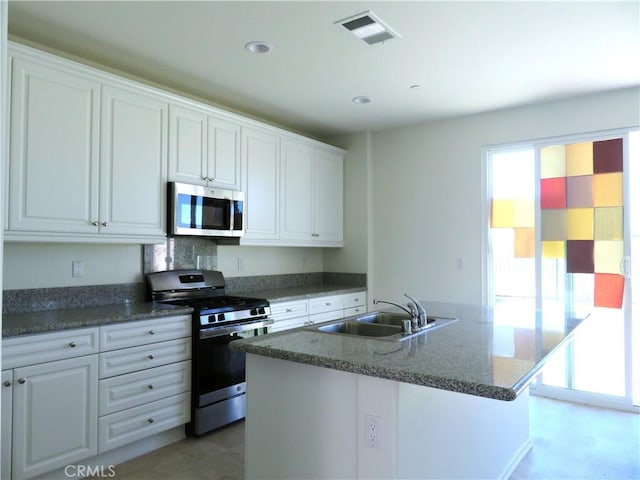 kitchen with white cabinets, a kitchen island with sink, sink, and appliances with stainless steel finishes