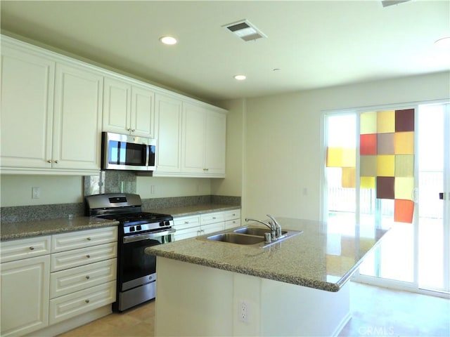 kitchen with sink, an island with sink, stone countertops, white cabinetry, and stainless steel appliances