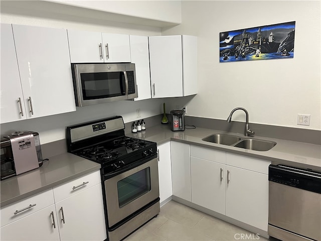 kitchen featuring light tile patterned floors, white cabinets, appliances with stainless steel finishes, and sink