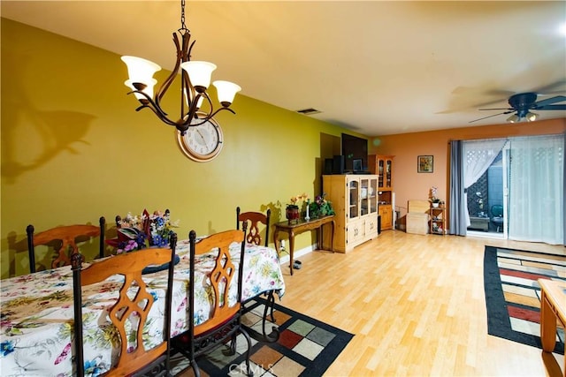 dining room with hardwood / wood-style floors and ceiling fan with notable chandelier