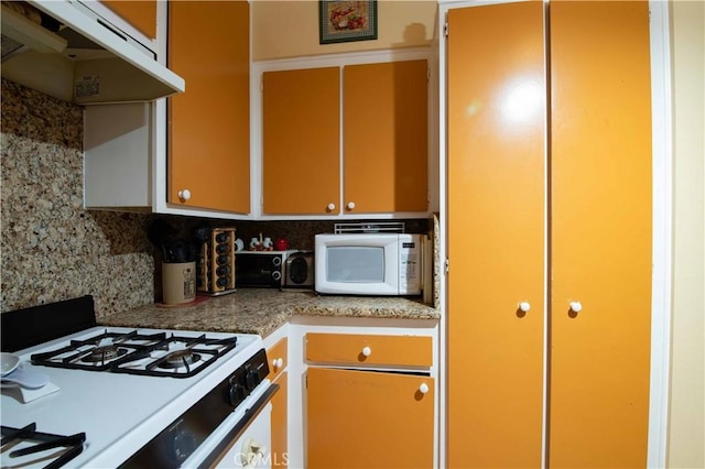 kitchen featuring white appliances, backsplash, and exhaust hood