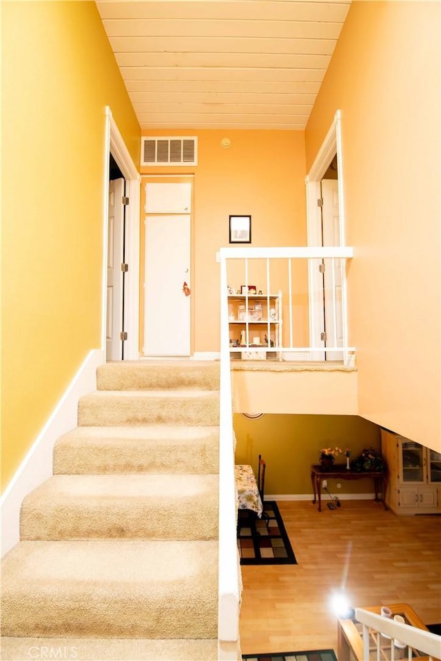 stairs with wood-type flooring and wooden ceiling