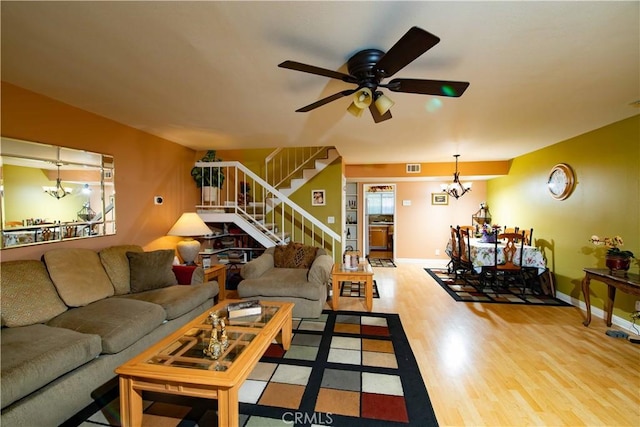 living room featuring ceiling fan with notable chandelier and light hardwood / wood-style floors