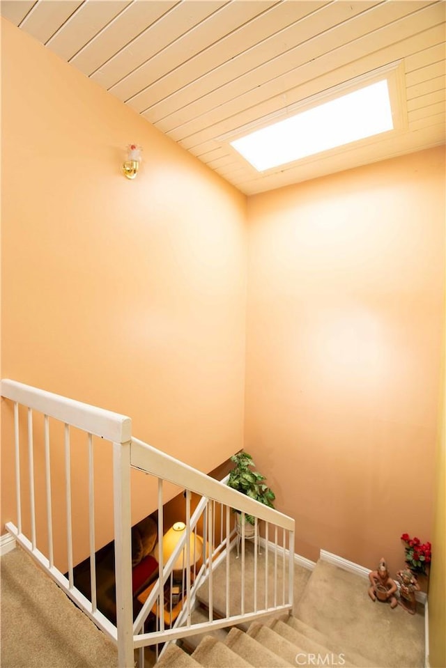 stairway with carpet, a skylight, and wood ceiling