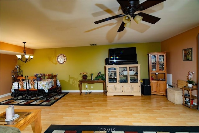 living room featuring ceiling fan with notable chandelier and light hardwood / wood-style floors