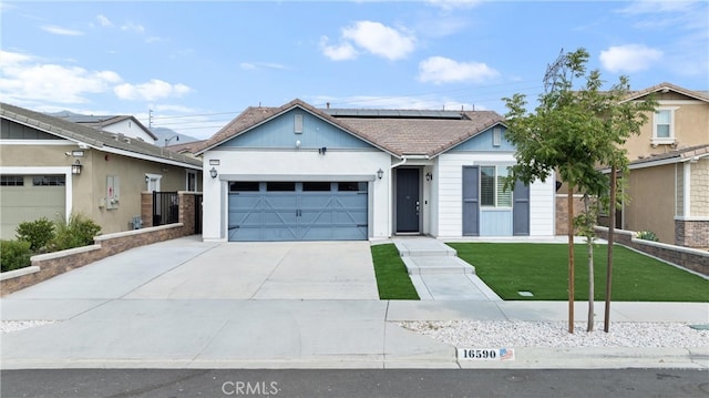 view of front of home featuring a garage, solar panels, and a front lawn