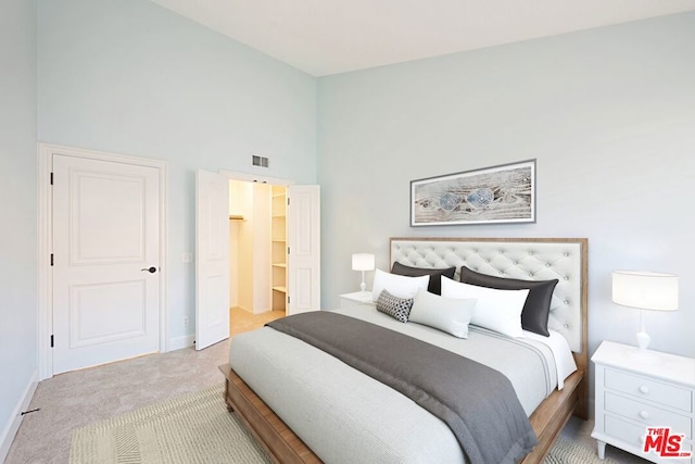 carpeted bedroom with a spacious closet and a towering ceiling