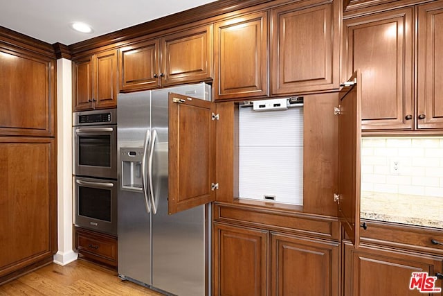 kitchen featuring light hardwood / wood-style floors, light stone counters, backsplash, and appliances with stainless steel finishes