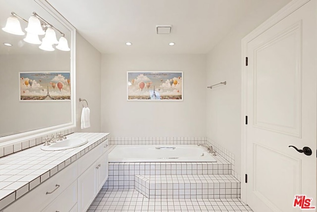 bathroom featuring tile patterned flooring, vanity, and tiled bath