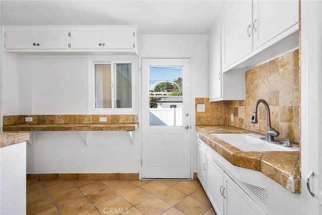 kitchen with backsplash, white cabinetry, sink, and light tile patterned flooring