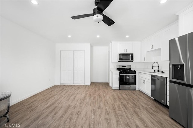 kitchen with appliances with stainless steel finishes, ceiling fan, sink, light hardwood / wood-style flooring, and white cabinetry