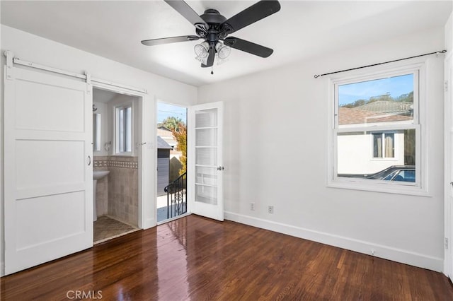 spare room with a barn door, dark hardwood / wood-style floors, and ceiling fan