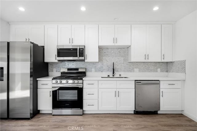 kitchen featuring white cabinets, appliances with stainless steel finishes, light hardwood / wood-style floors, and sink