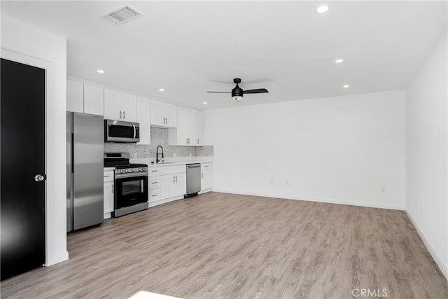 kitchen featuring white cabinetry, sink, light hardwood / wood-style flooring, decorative backsplash, and appliances with stainless steel finishes